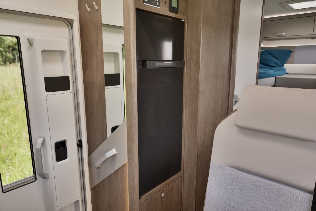 Carado motorhome interior with a tall fridge next to the entrance and the sleeping area in the background