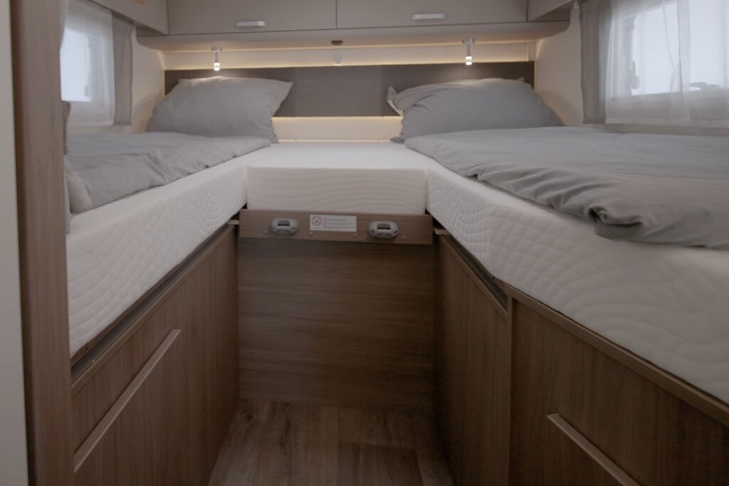 Sleeping area in the Carado motorhome with two single beds, centre cushion and storage space under the beds