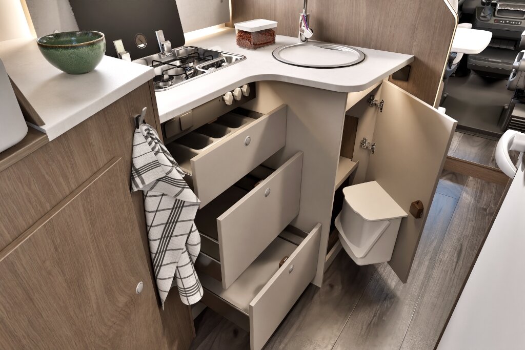 Carado motorhome interior with kitchen, open drawers and storage space under the sink and gas hob