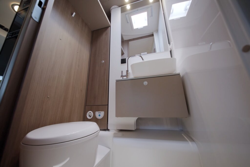 Bathroom in the Carado motorhome with toilet, washbasin, mirror and roof window