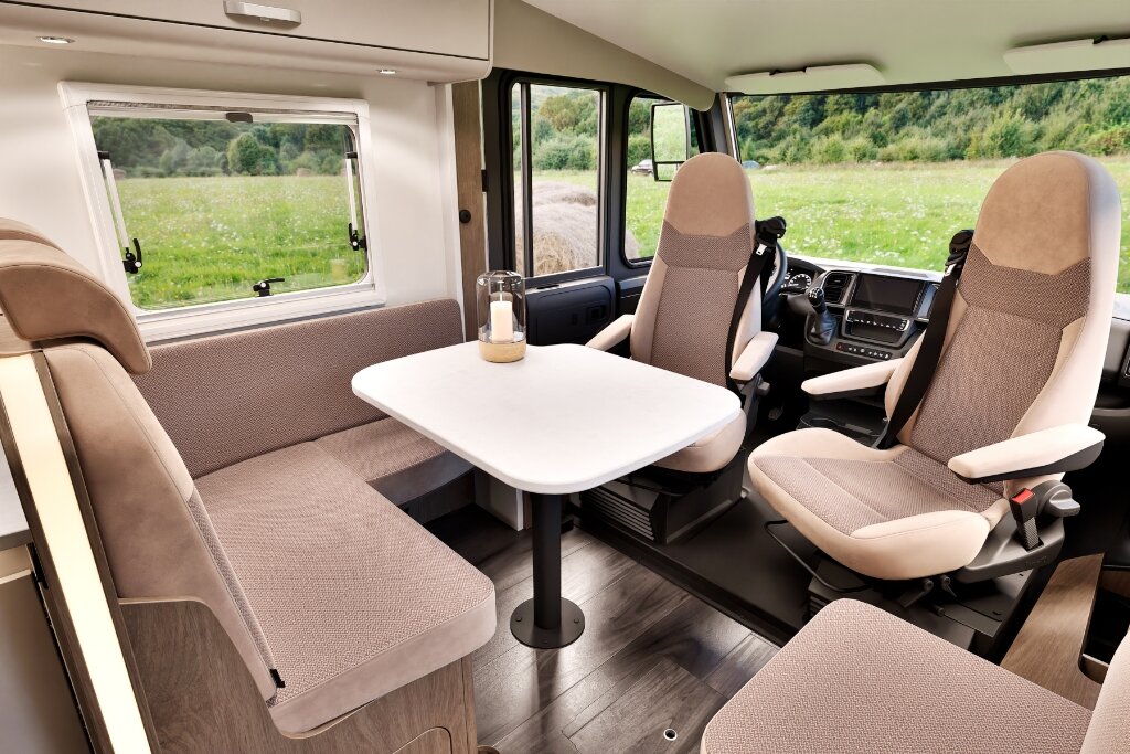 Carado motorhome interior with seating area, table and swivel cab seats
