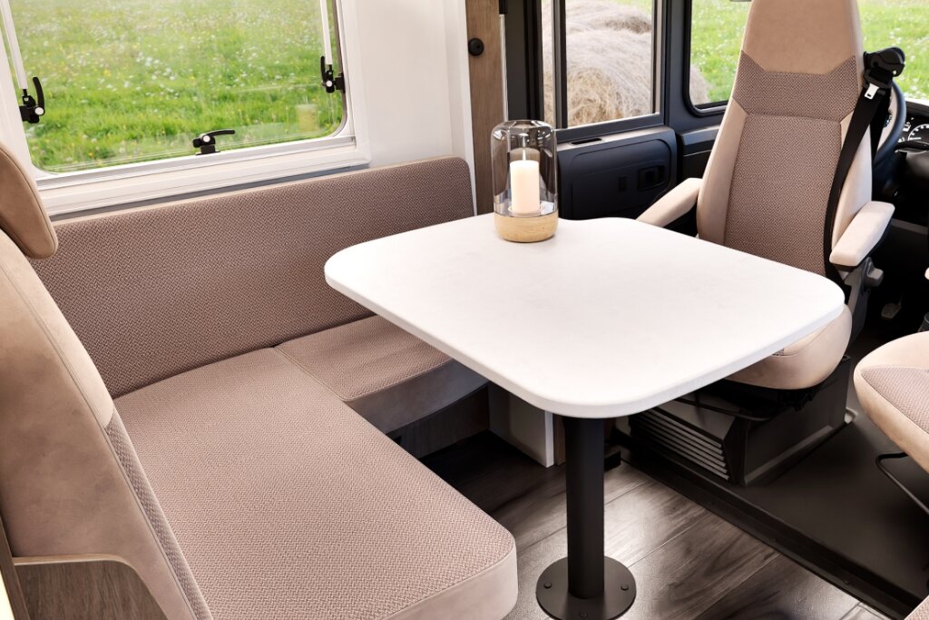 Seating area in the Carado motorhome with upholstered bench, table and swivel driver’s seat