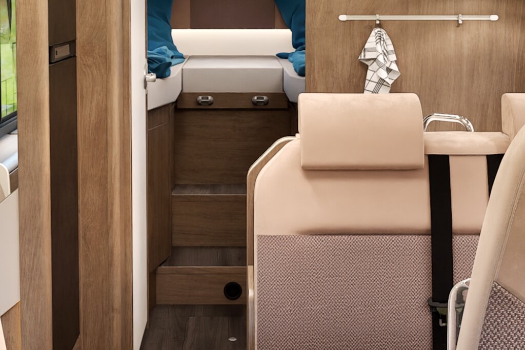 Carado motorhome interior with seating area, steps leading to the rear bed and wood-effect décor