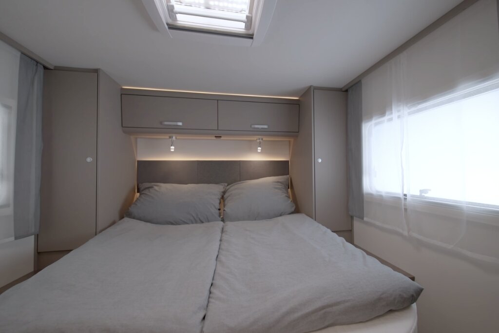Sleeping area in the Carado motorhome with double bed, roof window, overhead storage and side wardrobes