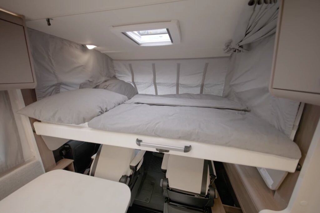 Cab-over bed in the Carado motorhome above the cab, with pillow, duvet and roof window