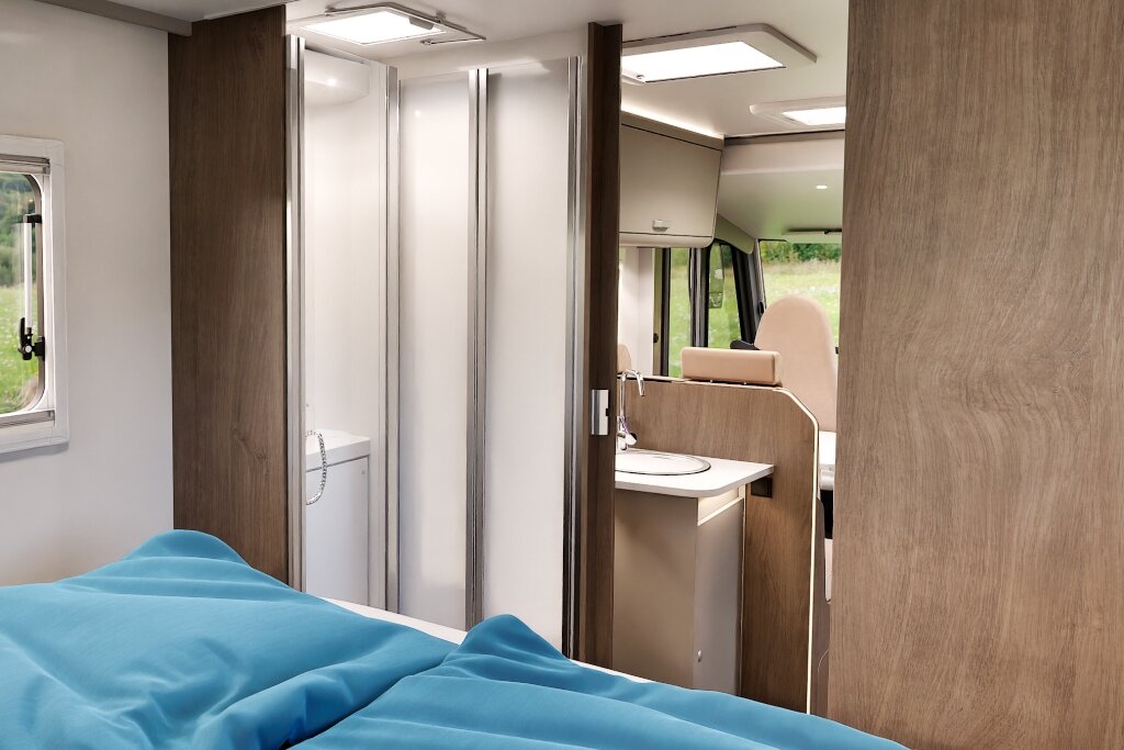 Sleeping area in the Carado motorhome with a view of the bathroom, shower and front seating area