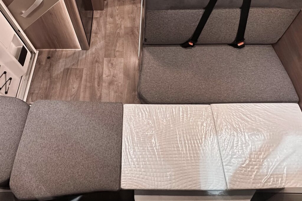 Carado motorhome seating area with converted sleeping space and grey upholstery in the interior