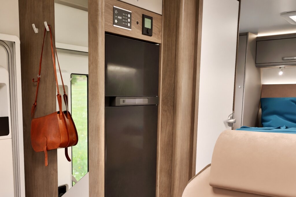 Carado motorhome interior with tall refrigerator, wood décor and a view toward the sleeping area
