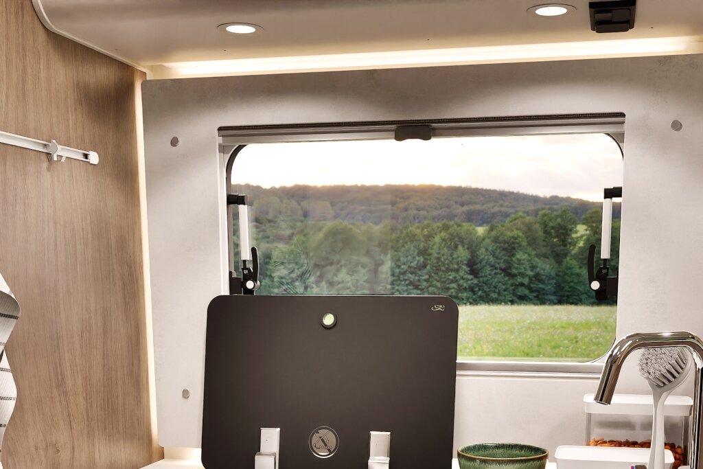 Carado motorhome interior with awning window, sink and a view over meadow and woodland