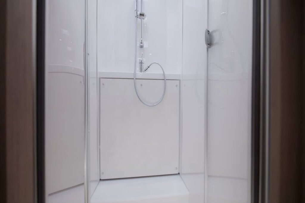 Shower cabin in the Carado motorhome with glass doors, handheld shower and white wet room