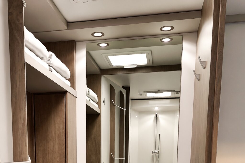 Carado motorhome interior with mirrored cabinet, roof window and shower area in the bathroom