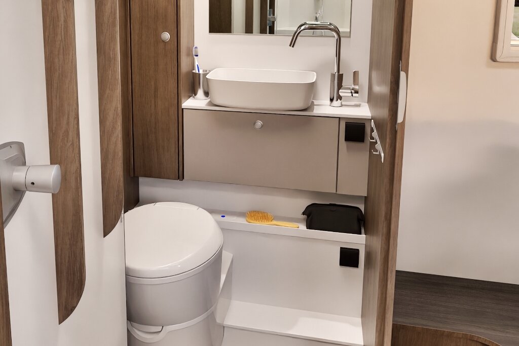 Bathroom in a Carado motorhome with cassette toilet, washbasin, mirror and wood decor