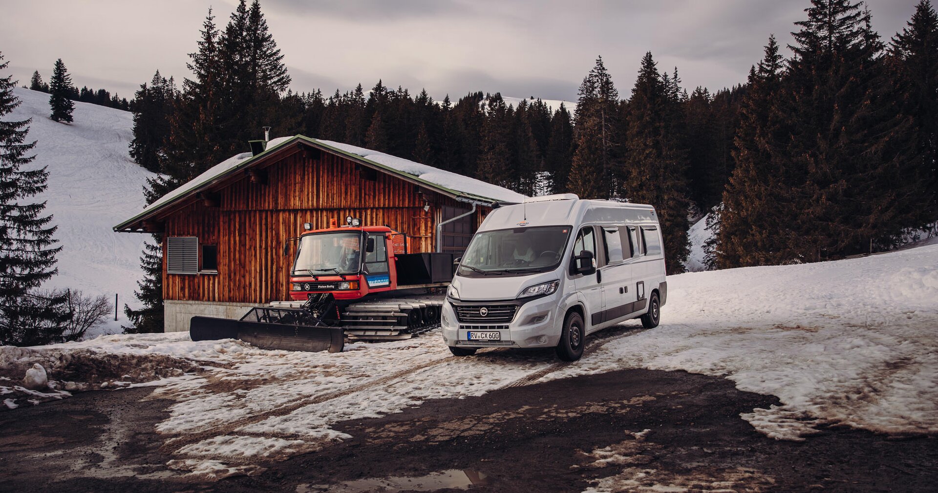 Camper Van im Winter mit Pistenbulli