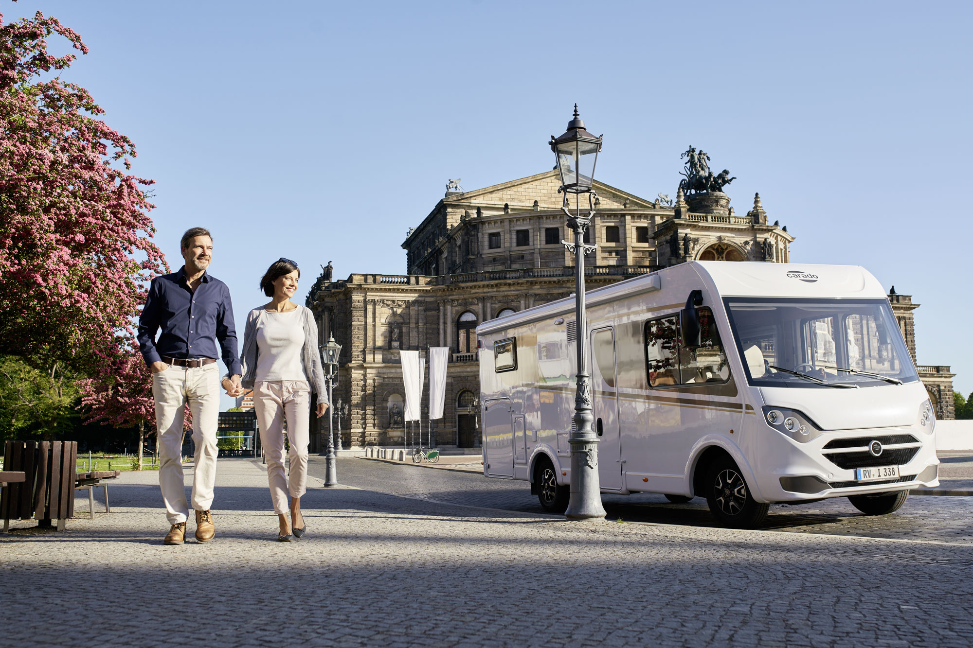 Ein Pärchen spaziert neben dem Carado durch eine Altstadt