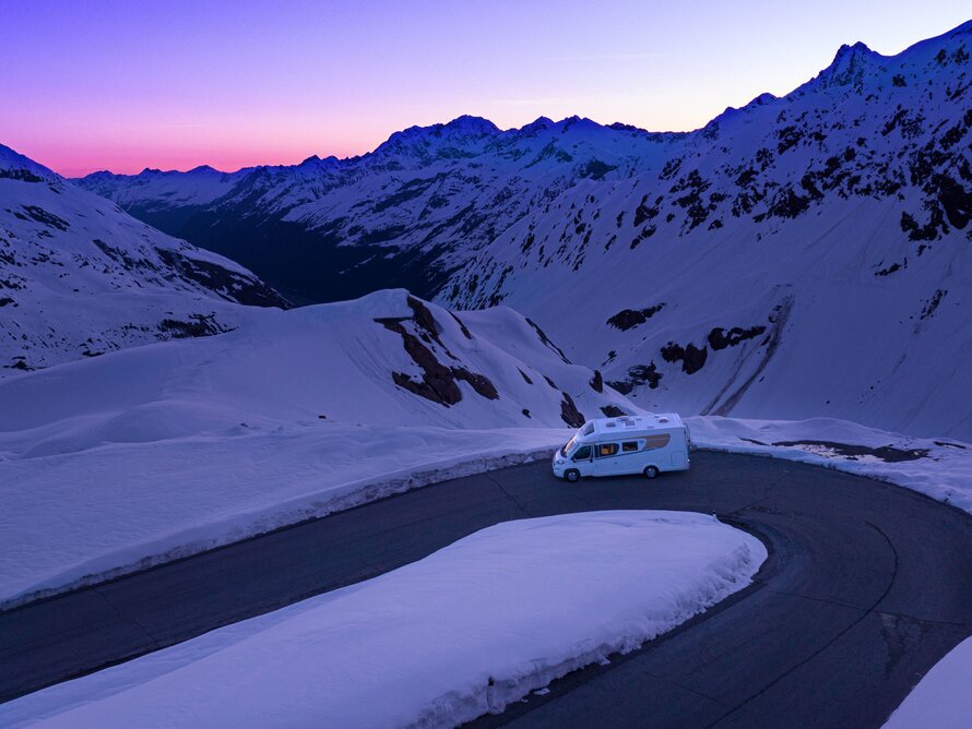 Das Wohnmobil fährt abends durch verschneite Berglandschaften
