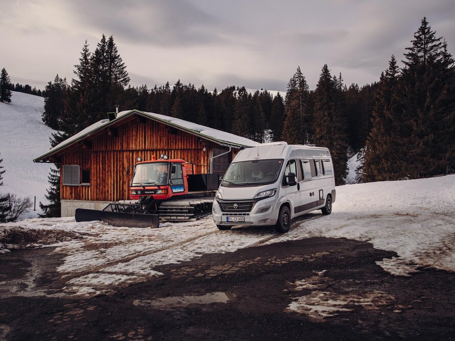 Camper Van im Winter mit Pistenbulli